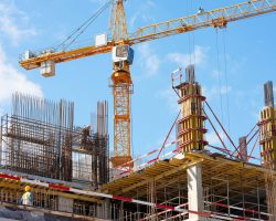 Construction site with cranes and building framework under a clear sky.