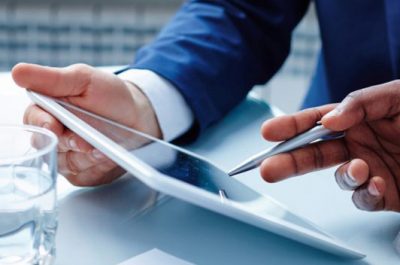 Two business professionals discussing data on a digital tablet during a meeting.