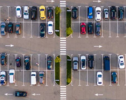 Aerial view of a busy parking lot with various cars and pedestrian crossings.