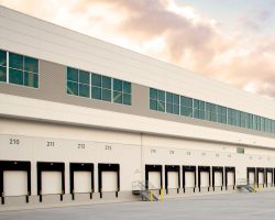 A large warehouse or distribution center with multiple loading docks under a partly cloudy sky.